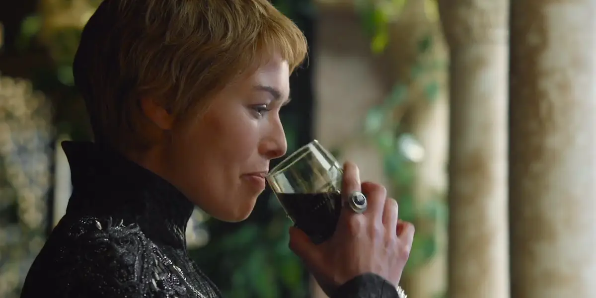 Cersei's face lit by candlelight in the Sept of Baelor, expression focused.